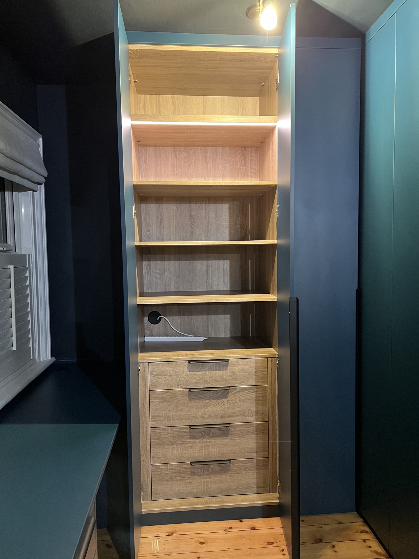 Illuminated wardrobe interior with shelves and integrated drawers