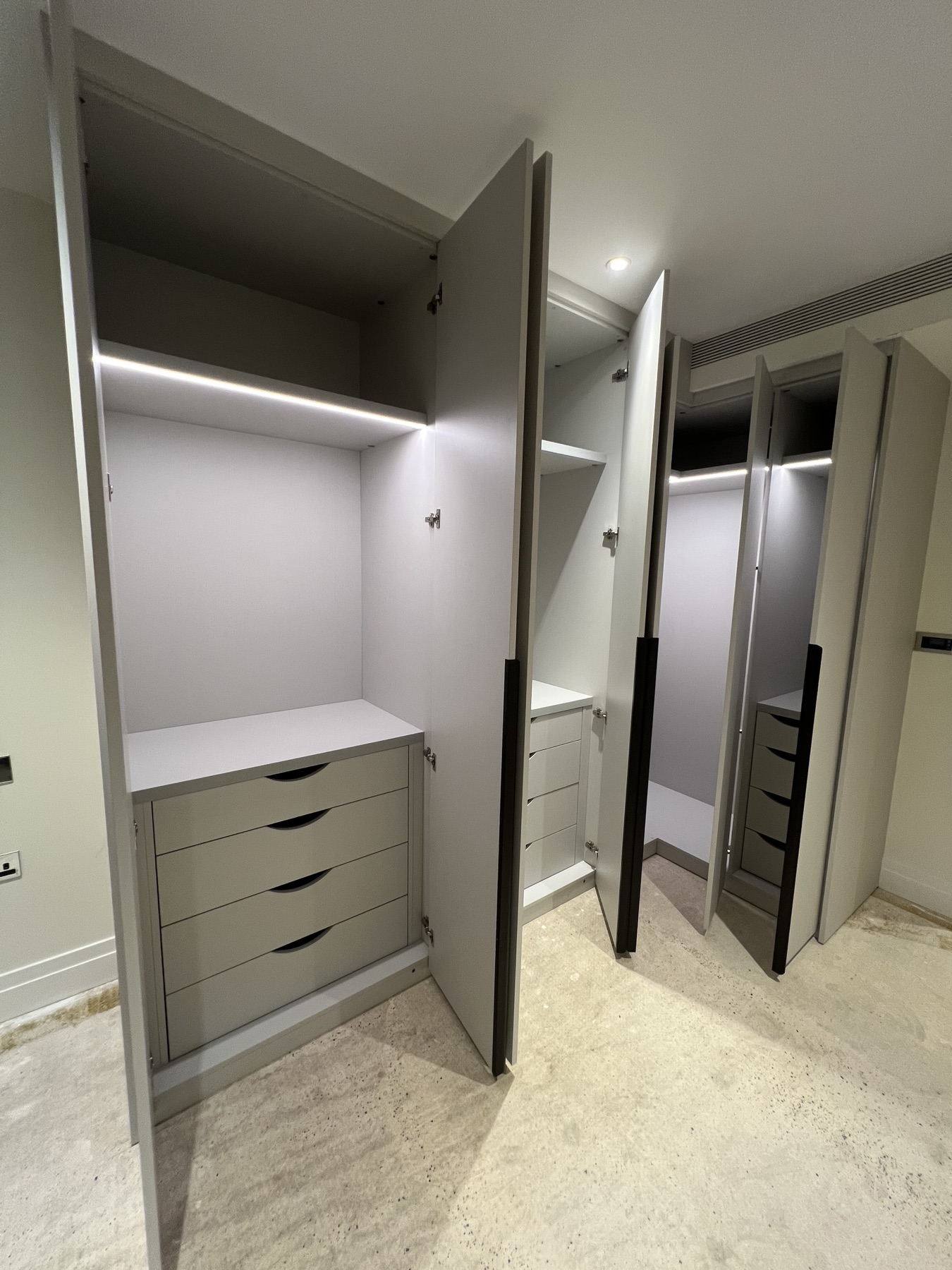Open fitted wardrobes showing internal drawers, shelves and lighting