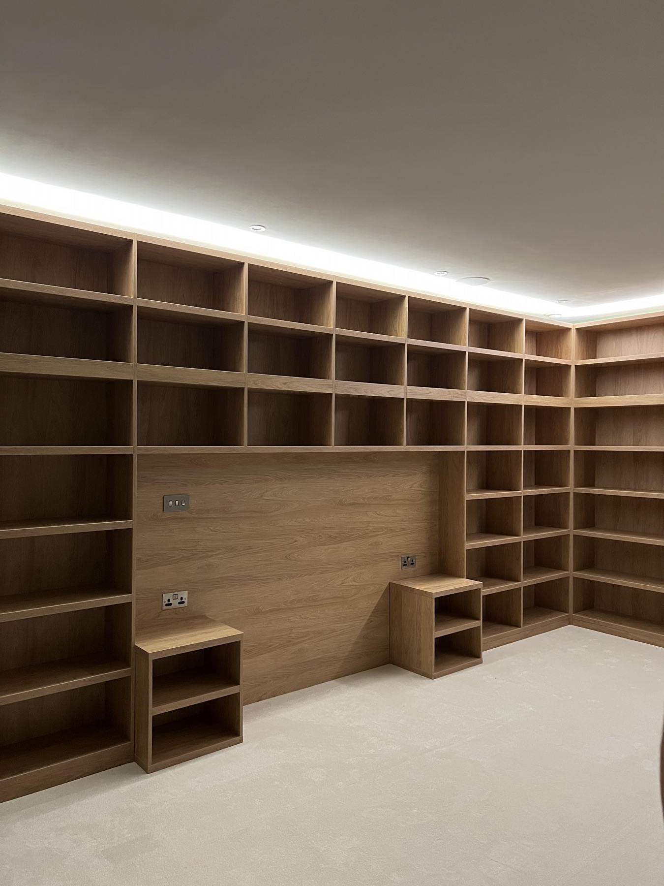 Completed wall-to-wall oak-effect shelving with integrated lighting