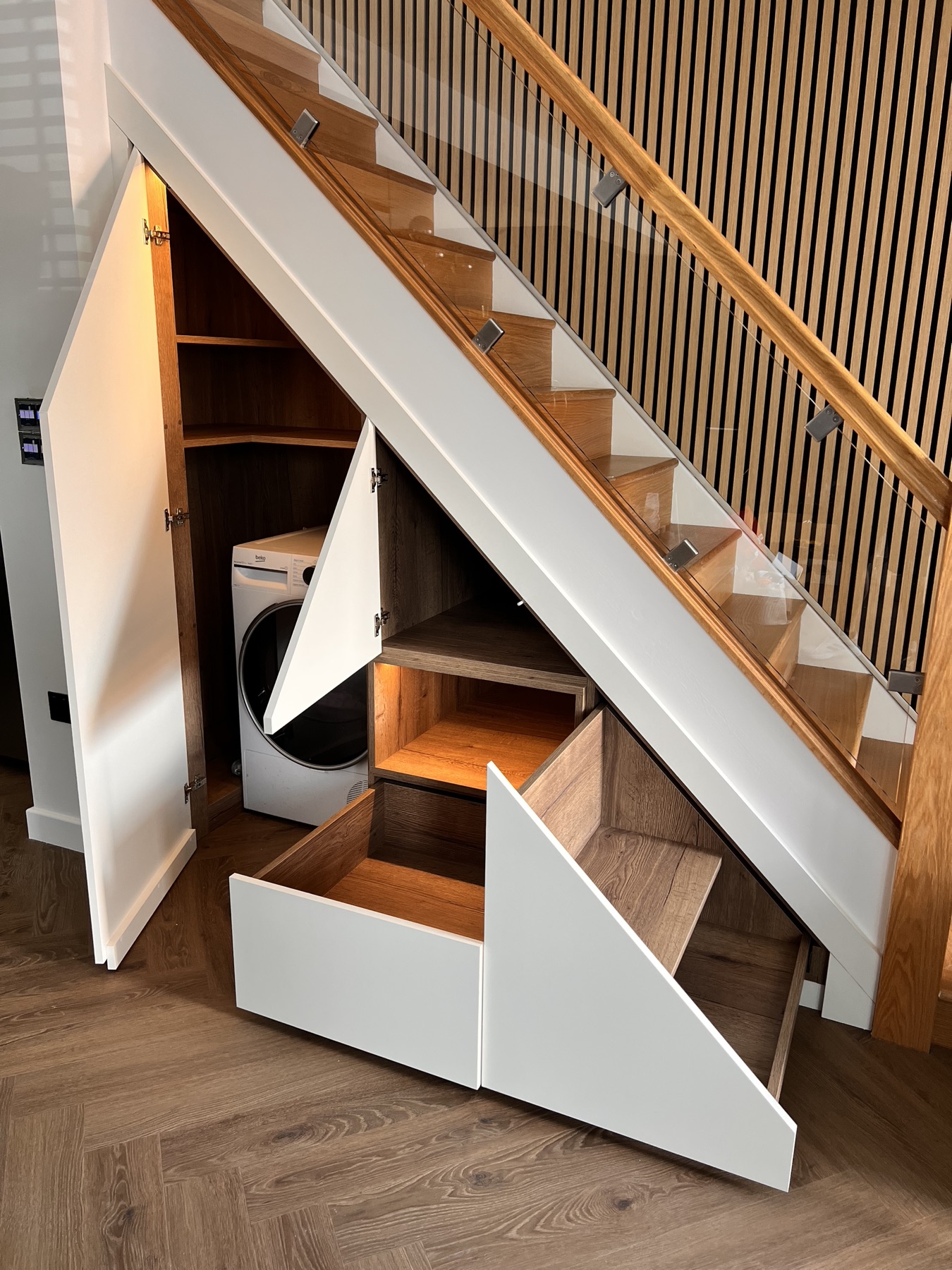 Open understairs cabinetry showing shelves, utility space and pull-out drawers